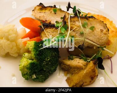 Filet de poulet cuit avec une casserole de pommes de terre, garni d'herbes et de légumes Banque D'Images