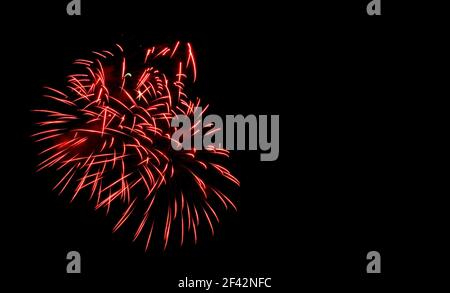 Gros plan sur les feux d'artifice dans le ciel. Banderoles rouges. Une exposition courte qui se traduit par une petite floraison. Espace pour le texte sur la droite. Banque D'Images