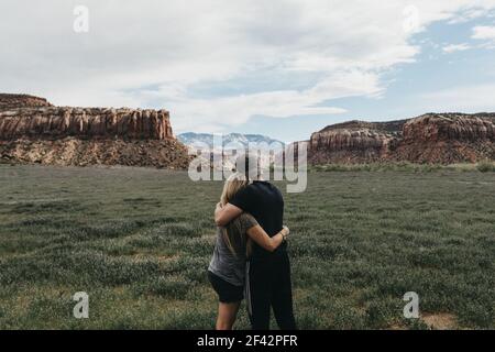 couple embrassant dans le champ avec des montagnes Banque D'Images