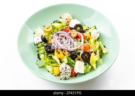 salade grecque dans une assiette verte sur fond blanc Banque D'Images