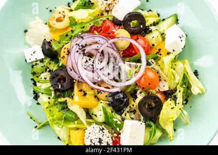 salade grecque dans une assiette verte sur fond blanc Banque D'Images