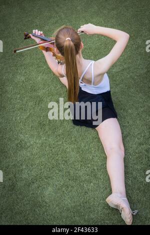 fille dans le ballet spagat pose jouant le violon sur le vert herbe placée en diagonale sur l'image Banque D'Images