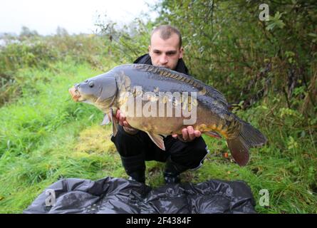 Le pêcheur à la ligne a attrapé un gros poisson et pose pour les photos Banque D'Images