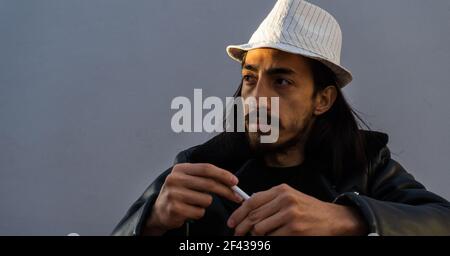 homme à la mode tenant une cigarette, sur le point de fumer à l'heure d'or. photo panoramique. espace de copie Banque D'Images