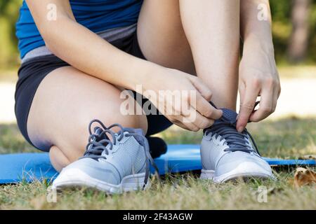 female hands tying shoelace on running shoes before practice Stock Photo