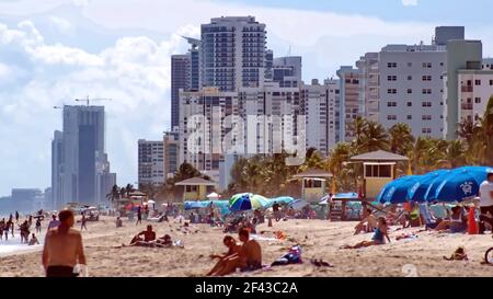 Touristes avec parasols colorés sur Dania Beach, avec des hôtels et des condos en arrière-plan, fort Lauderdale, Floride, États-Unis Banque D'Images