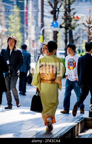 Vue arrière sur toute la longueur de la femelle japonaise marchant à travers Ginza portant un kimono sous le soleil de l'après-midi, Tokyo, Japon Banque D'Images