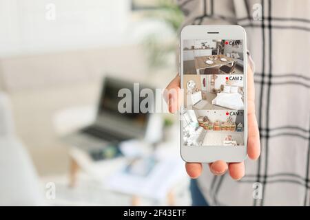 Femme montrant un téléphone portable avec des images de caméras cctv installées dans l'appartement à l'écran, en gros plan Banque D'Images