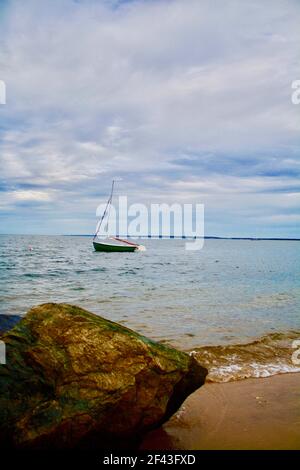 Plan vertical d'un Lone Voilier sur l'eau, Gardiners Bay dans East Hampton, long Island New York avec grand Boulder dans le premier plan Banque D'Images
