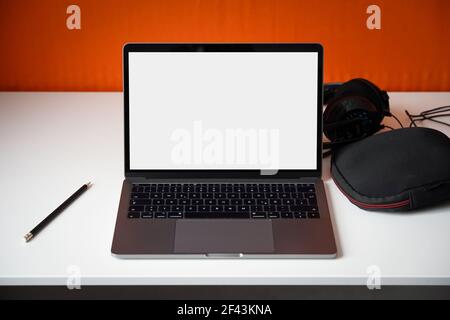Ordinateur portable sur un bureau avec écran blanc. Configuration du bureau à domicile pour le travail mobile. Ordinateur avec écran lumineux. Banque D'Images