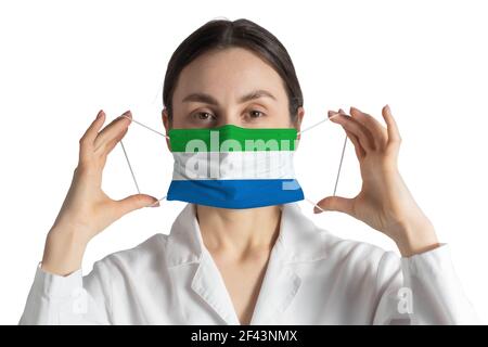 Respirateur avec drapeau de Sierra Leone le docteur met sur le masque médical isolé sur fond blanc. Banque D'Images