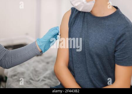 Gros plan du médecin utilisant du coton avant de faire l'injection au patient dans le masque médical. Vaccin Covid-19 ou coronavirus pour garçon Banque D'Images