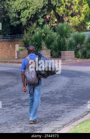 Johannesburg, Afrique du Sud - un homme sans abri non identifié descend dans la rue en portant toutes ses affaires Banque D'Images