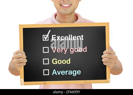 Marque de graduation devant le mot excellent sur le tableau noir tenu par homme souriant - concept d'évaluation et de feedback Banque D'Images