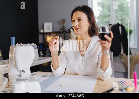 Adorable un designer qui boit du vin et qui esquisse Banque D'Images