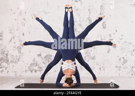 Une femme pratiquant le yoga, effectuant un exercice d'asana inversé, de tête, de shirshasana avec différentes positions de jambes sur un tapis près du mur. La sy Banque D'Images