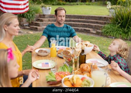 L'homme et la famille caucasiens tiennent les mains pour dire grâce avant de manger repas ensemble dans le jardin Banque D'Images