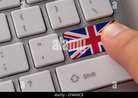 Homme main appuyant sur le bouton du clavier avec drapeau de la Grande-Bretagne dessus. Concept d'affaires internationales en ligne. Banque D'Images