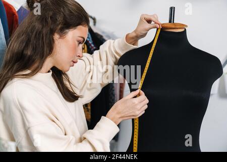 Portrait d'une jeune femme de créateur avec mannequin ou mannequin travaillant en studio, mesurant Banque D'Images