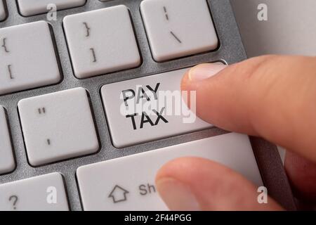 Homme main appuyant sur le bouton du clavier PAYER TAXE. Business Online concept. Banque D'Images