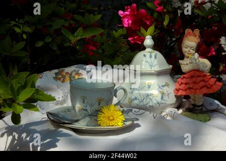 table basse avec tasse et bol à sucre ancien prêt pour le café, parmi les fleurs colorées et les décorations millésimes Banque D'Images