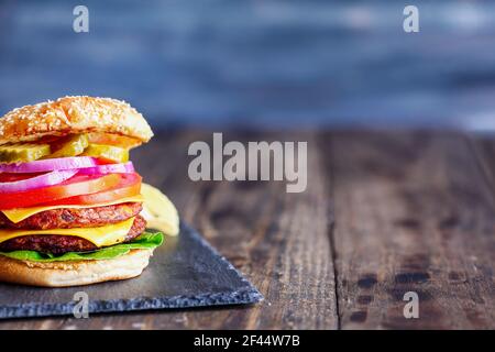 Cheeseburger végétarien préparé avec deux viandes de substitution, des tranches de fromage fondu, des oignons, des cornichons, de la laitue et de la tomate sur un bobu de graines de sésame frais Banque D'Images