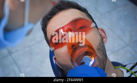 dentiste avec lampe à ultraviolet près du patient dans des lunettes, avant-plan flou Banque D'Images