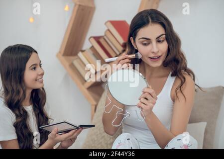 Femme faisant le maquillage et la fille regardant intéressé Banque D'Images