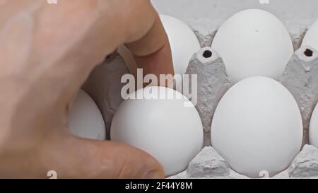 vue rognée de l'homme prenant l'œuf de l'emballage, vue rapprochée Banque D'Images
