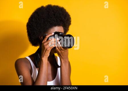 Gros plan portrait d'une fille de brunette à cheveux ondulés tenant dans les mains en utilisant capture de caméra isolée sur fond jaune vif Banque D'Images