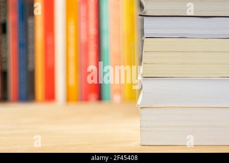 Pile de livres devant des livres non focalisés sur une table en bois. Banque D'Images