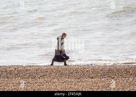 Un promeneur de chien solitaire près de la mer sur la plage d'Hythe, Kent. Banque D'Images