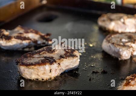 Côtelettes de porc désossées marinées cuisant sur un style hibachi en extérieur grande plaque chauffante Banque D'Images