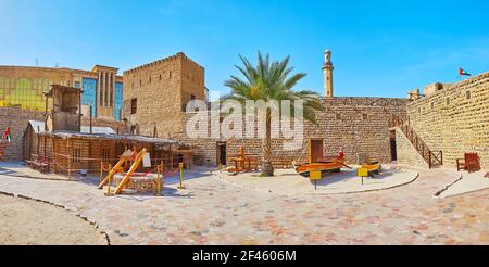 Panorama du fort Al Fahidi avec grand rempart, tour, bateaux de pêche en bois d'époque et la maison d'été arish, faite de branches de palmier et de fibres, Dubaï, Banque D'Images