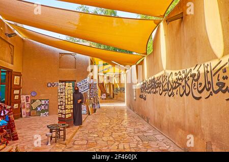 DUBAÏ, Émirats Arabes Unis - 8 MARS 2020 : l'étroite rue ombragée avec un auvent, la calligraphie sur le mur d'adobe et les sotres souvenirs d'Al Souk al Kabir (ancien marché) Banque D'Images