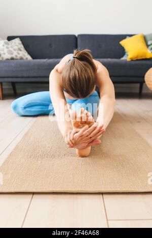 Portrait d'une jeune femme pratiquant le yoga à l'intérieur. Femme pratique janu sirsasana à la maison. Banque D'Images