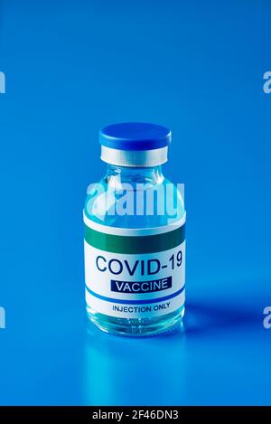 flacon simulé d'un vaccin covid-19, avec une étiquette indiquant uniquement l'injection du vaccin covid-19, sur fond bleu Banque D'Images