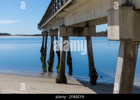 Pilages de quai en béton menant à Tybee Creek, ciel bleu clair reflété dans les eaux fixes, Tybee Island Georgia, aspect horizontal Banque D'Images