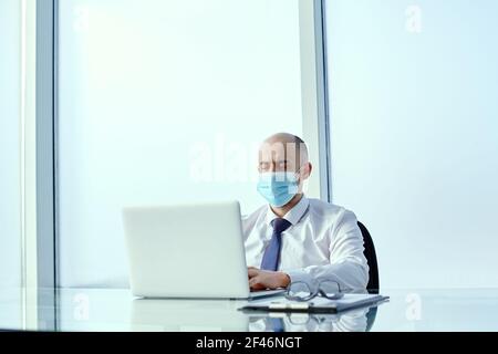 homme d'affaires avec un masque de protection travaille sur un ordinateur portable dans le bureau. Banque D'Images