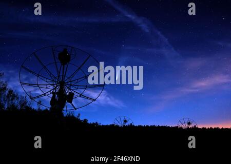 radiotelescopes silhouettes sous nuit étoilée ciel nuageux fond Banque D'Images