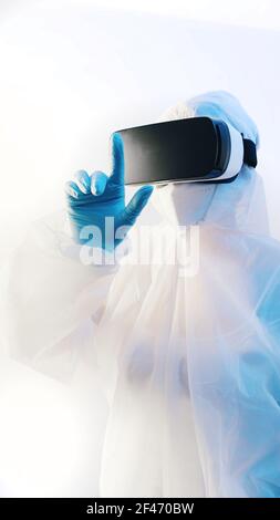 Médecin ou infirmière en combinaison de protection complète avec des lunettes vr touchant l'air. Photo de haute qualité Banque D'Images