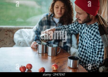 Couplez dans un guimauve à motif écossais à carreaux au feu près de la remorque. Banque D'Images