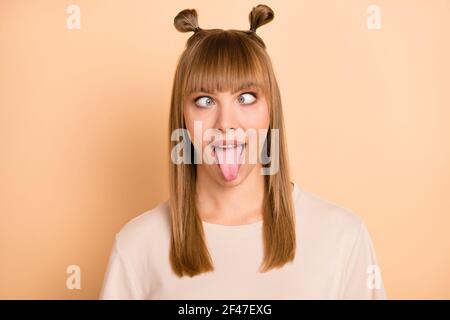 Photo portrait d'une fille folle enfantine montrant la langue grimace port t-shirt isolé sur fond beige pastel Banque D'Images