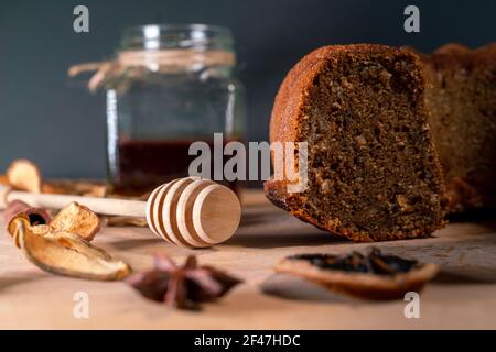 Encore la vie avec un gâteau maison, un pot avec du miel et du balancier, de la cannelle, des fruits secs, de l'anis étoilé sur un panneau de bois. Petits en-cas sains à déguster pendant Banque D'Images