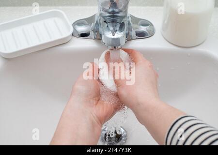 Femme se lavant les mains avec du savon dans la salle de bain Banque D'Images