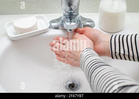 Femme se lavant les mains avec du savon dans la salle de bain Banque D'Images