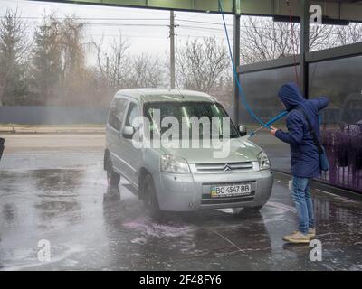 Un homme couvre un auto avec de l'eau à un libre-service lavage de voiture Banque D'Images