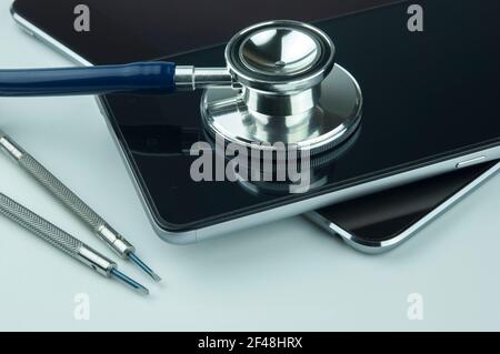 Stéthoscope, smartphone, tablette et tournevis. Concept de réparation et de service de smartphone. Concept un état de santé de l'appareil. Banque D'Images