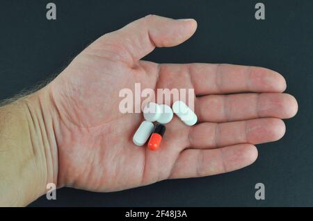 Pilules en main sur fond gris foncé. Concept de prendre votre médicament. Banque D'Images