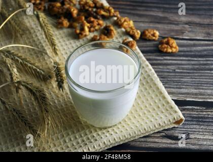 Verre de lait gros plan, noix caramélisées sur une serviette de cuisine. Banque D'Images